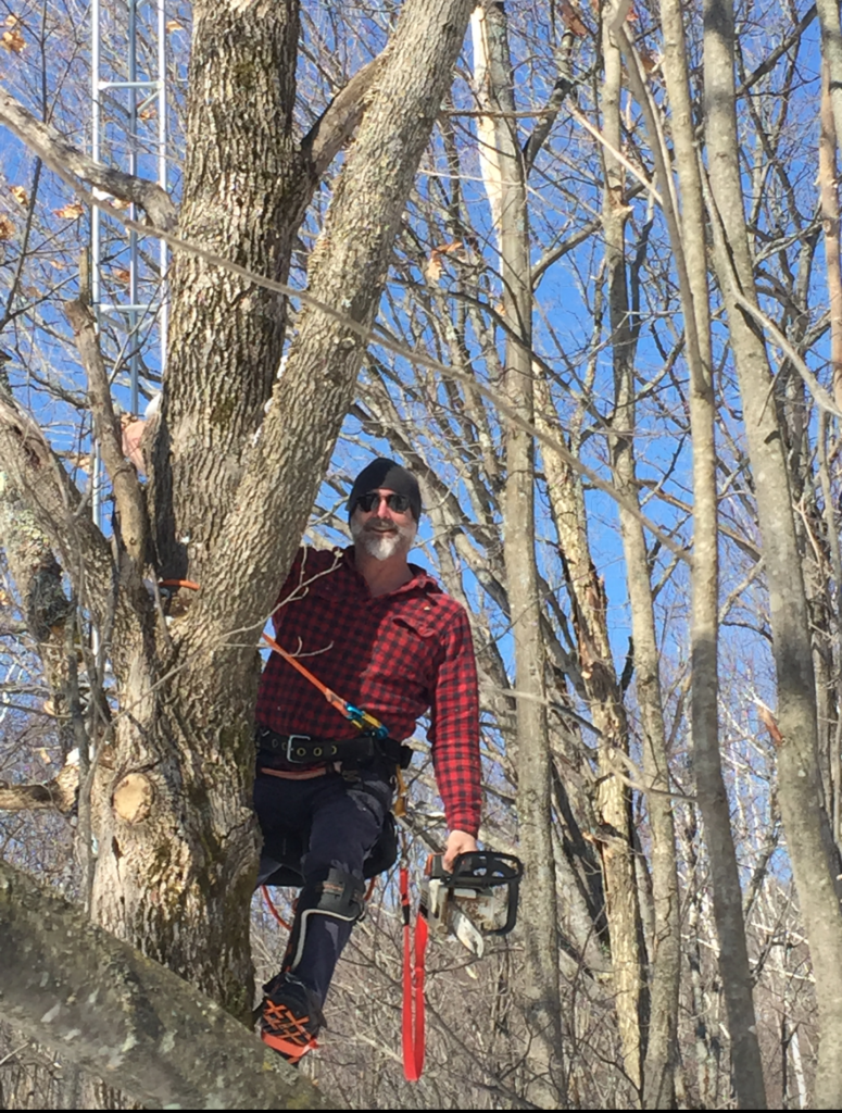 A man standing in the woods with a pole.
